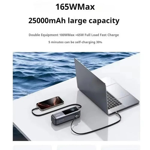 Anker 25000mAh portable charger charging a laptop and smartphone by the sea.